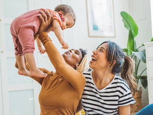 Young mothers playing with baby girl in living room. Source: Getty Images. Credit: svetikd