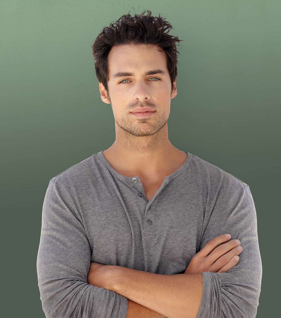Man with short dark hair wearing a gray long-sleeve henley shirt, standing with arms crossed against a muted green background.