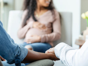 Prospective adoptive parents hold hands while meeting with pregnant woman (Source: Getty Images. Credit: SDI Productions)